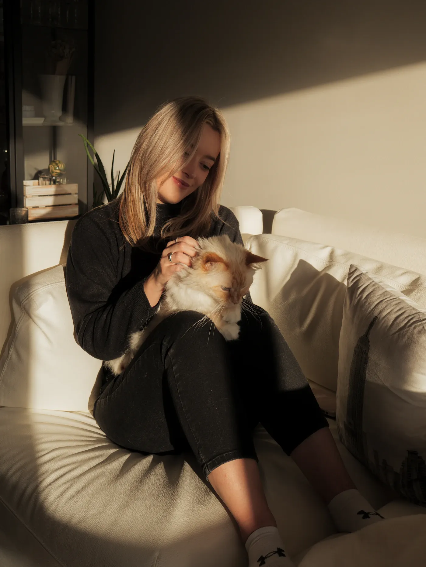 A woman holding her cat in warm afternoon light at home